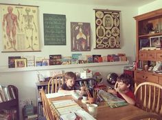 two young boys sitting at a table in front of books and posters on the wall