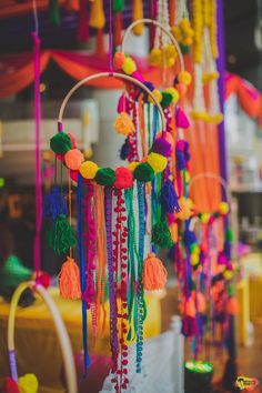 an assortment of colorful beads hanging from the ceiling in front of a table with candles and decorations on it