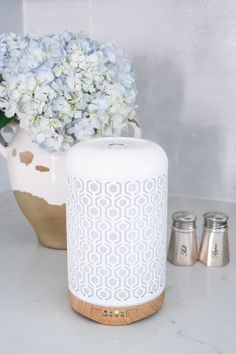 a white vase filled with flowers next to two salt and pepper shakers on a counter