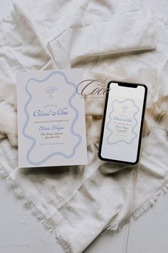 an open cell phone sitting on top of a white blanket next to a card and envelope