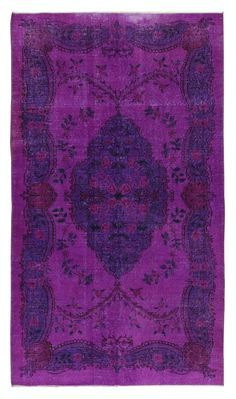 a purple rug with an ornate design on the center and sides, in different colors