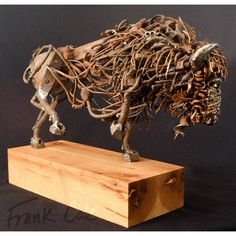 a sculpture of a cow made out of metal wire and wood on a wooden block