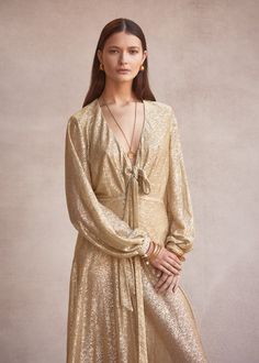 The Fontana Maxi Dress in Gold Supernova features a V-neckline with front tie, long balloon sleeves with elastic cuff with gold button detailing. The dress is a relaxed fit through the bodice with a full maxi skirt that falls from a fitted panel across the hip with side zip. Made in soft, stretch metallic tulle, the fabrication features a tiny gold sequin pattern that gives a subtle shimmer. Ultra-light, soft and semi sheer, this dress is relaxed and elegant. Product Details: Fabric sourced in K Sequin Pattern, Full Maxi Skirt, Dress Gold, Maxi Dress Navy, Long Balloons, Gold Sequin, Gold Dress, Balloon Sleeves, Gold Buttons