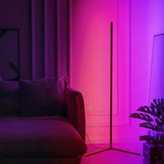 a living room filled with furniture and purple lighting on the walls, next to a couch