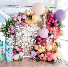 a table topped with lots of balloons next to boxes filled with fruit and greenery