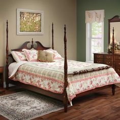 a bed sitting on top of a wooden floor next to a dresser and mirror in a bedroom