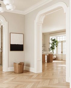 an empty living room with white walls and wood flooring, framed art on the wall