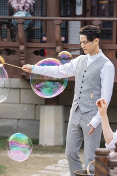 a young man in a suit and tie is playing with soap bubbles while another person watches