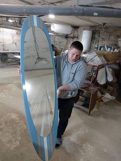 a man standing next to a surfboard in a garage