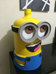 a yellow and blue minion with big eyes on top of a black table next to a white wall