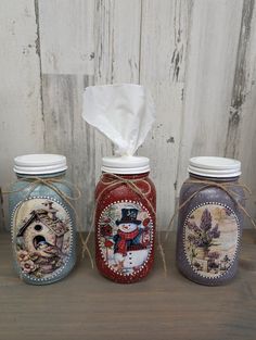 three jars with different designs on them and one has a tissue dispenser