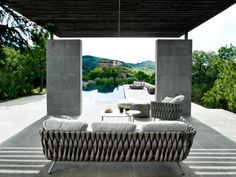 an outdoor living room with couches and tables next to a pool in the background