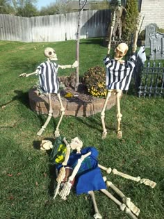 two skeletons sitting on top of a lush green field next to a dead man in a black and white striped shirt