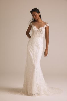 a woman in a wedding dress posing for the camera with her hands on her hips