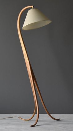 a wooden floor lamp with a white shade on the base and a black cord attached to it