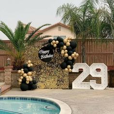 a pool with a sign and balloons in the shape of numbers next to a swimming pool