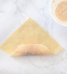 a piece of cheese sitting on top of a counter next to a bowl and spoon