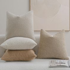 two pillows and a pillow on a couch with a magazine in front of the cushion