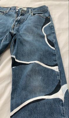 an old pair of jeans is laying on a white sheet with black and blue designs