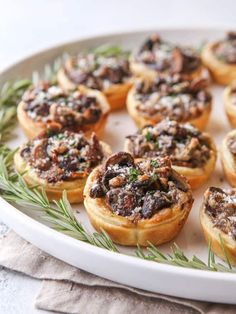 small appetizers are arranged on a plate with rosemary sprigs and seasoning