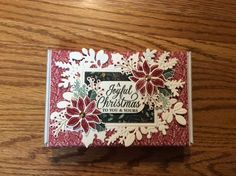 a christmas card with poinsettis on it sitting on top of a wooden table