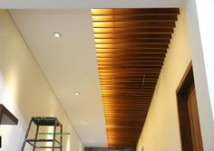 an empty hallway with wooden slats on the ceiling and ladders in front of it