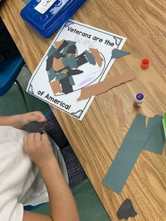 a young boy is cutting out pieces of paper on the table with scissors and glue