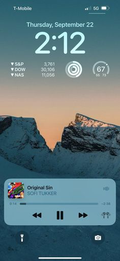 an iphone screen with the clock displayed on it and mountains in the backgroud