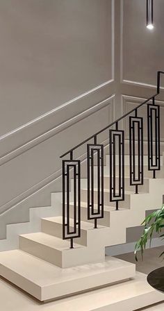 a plant sitting on top of a white table next to a stair case with black railings