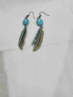 Native American inspired.  Just under 3" in length.  Feather with turquoise glass seed beads and a larger turquoise bead, all on a hook Turquoise Large Beads Drop Earrings, Turquoise Metal Jewelry With Dangling Beads, Turquoise Jewelry With Colorful Metal Beads, Turquoise Drop Earrings With Large Beads, Turquoise Metal Beaded Bohemian Earrings, Handmade Turquoise Metal Bead Jewelry, Adjustable Turquoise Earrings With Large Beads, Turquoise Dangle Earrings With Large Beads, Handmade Turquoise Jewelry With Metal Beads