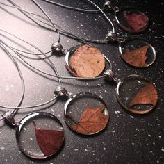 four necklaces with leaves in them on a table