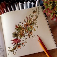 an open book with flowers on it next to a pencil