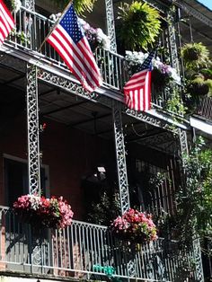 an old building with american flags on the balconies and flowers in hanging baskets