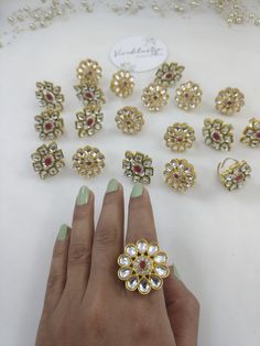 a woman's hand with green fingernails and gold jewelry on the table next to it