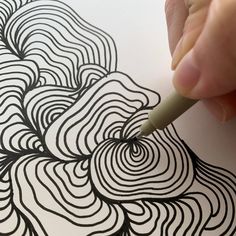 a person is drawing on paper with a pen and inking the lines in black and white