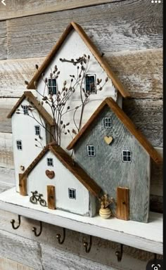 two white houses are sitting on a shelf with hooks and keys hanging from the wall