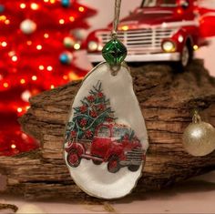 a glass ornament with a red truck and christmas tree on it next to a decorated christmas tree