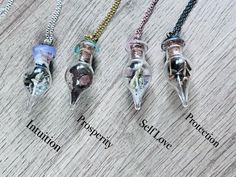 four necklaces with different types of skulls on them sitting on top of a wooden table