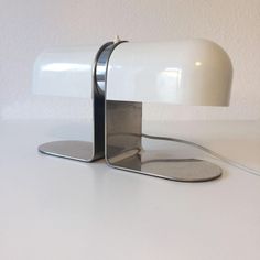 a white table lamp sitting on top of a white counter next to a light bulb