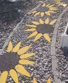 there are sunflowers painted on the side of the road with rocks and gravel