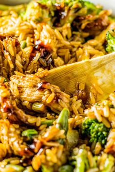 broccoli and rice is being stirred with a wooden spoon