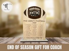 a football trophy sitting on top of a table next to a wooden plaque that says, end of season gift for coach