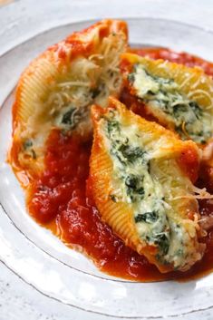 two stuffed shells with sauce and cheese on a white plate, ready to be eaten