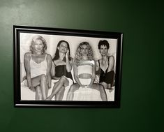 black and white photograph of four women in bathing suits hanging on the wall next to a toilet