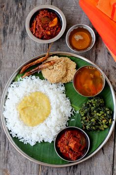 a plate filled with rice, sauces and other food on top of a wooden table