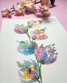 some flowers are sitting on top of a piece of paper with watercolor paint and sprinkles