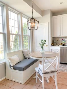 a kitchen with a table and chairs next to a window in the room that has white cabinets