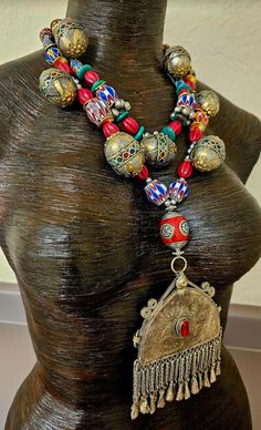 Here's a gorgeous, wild and exotic tribal or ethnic beaded statement necklace - chest piece from my private vault. New and unworn. The vintage pendant, which measures 4.5" x 3.75" is from the Middle East, etched and has a piece of red inlaid glass to ward off the "evil eye." All of the attached dangles are intact which is rare for pieces of this age and genre. A double strand necklace supports the pendant and features the following components: chevron beads, red oval "squash" beads, shiny silver balls, African hand painted glass, bone, ornate metal Turkman beads with possible inlaid gemstones, turquoise slices, gold tone metal wavy potato chip spacers, tiny silver tone vintage bells and a large red Tibetan resin inlaid focal bead. This lightweight piece adjusts from 19-22" and is finished Bohemian Jewelry With Polished Beads For Traditional Ceremonies, Red Bohemian Necklaces For Traditional Ceremonies, Bohemian Red Necklaces For Traditional Ceremonies, Bohemian Beaded Necklaces For Traditional Ceremonies, Bohemian Ceremonial Necklaces With Polished Beads, Bohemian Beads For Festivals, Bohemian Ceremonial Necklace With Large Beads, Bohemian Necklace With Large Beads For Ceremonial Use, Bohemian Necklace With Large Beads For Ceremonial Occasions