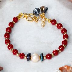 Beautiful Red coral, Pearl and gold plated Hematite bracelet designed and handcrafted with care and attention to detail. The bracelet is  hand threaded onto quality 19 strand beading wire for flexibility and durability using:     6mm dyed Red Coral beads,     Freshwater pearl focal bead,     2mm Gold plated Hematite beads,      Dark blue wavy Picasso Czech glass accent disc     beads.  The bracelet measures 19cm and is fastened using a quality 18ct gold plated toggle clasp which is adorned with Red Pearl Beaded Bracelet Perfect As A Gift, Red Pearl Beaded Bracelets As Gift, Red Pearl Bracelet As A Gift, Red Pearl Bracelets As A Gift, Red Pearl Bracelet As Gift, Handmade Red Pearl Bracelet With Round Beads, Red Pearl Bracelets For Gifts, Red Pearl Bracelet Gift, Red Pearl Bracelets For Gift