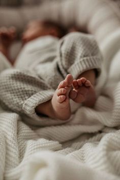 a baby laying on top of a white blanket